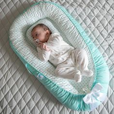 a baby laying on top of a blue and white blanket next to a pillow with a pacifier in it's mouth