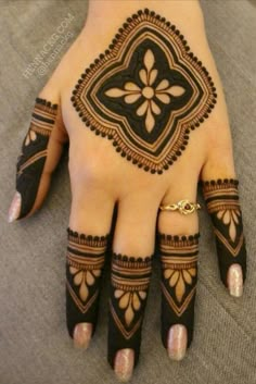 a henna tattoo on the palm of someone's hand, with gold rings