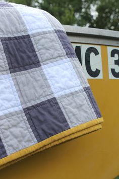 a close up of a quilt on the back of a yellow and white boat with trees in the background