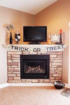 a fireplace with a trick or treat sign on it and a tv above the fire place