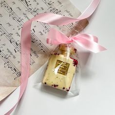 a piece of cake in a bag on top of sheet music paper with pink ribbon