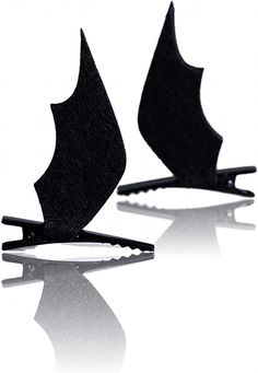 two pieces of black hair clips sitting on top of a white surface with one piece cut out to look like a bat