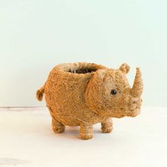 an animal made out of yarn sitting on top of a white table next to a wall