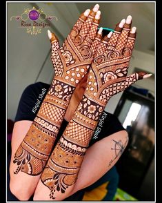 two hands with henna tattoos on them, one is showing off the intricate design