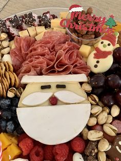 a platter filled with different types of christmas food and nuts, including meats, cheeses, fruit, and candy