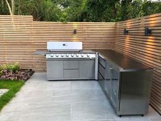 an outdoor kitchen with stainless steel appliances and wood slats on the wall behind it