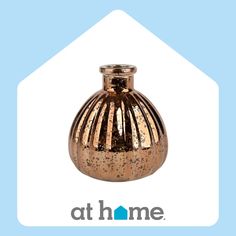 a gold colored vase sitting on top of a blue and white background with the words at home above it