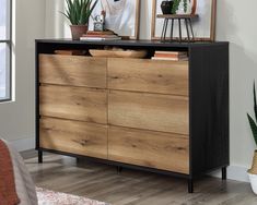 a black and brown dresser with plants on top