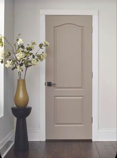 a vase with flowers sitting in front of a door on a hard wood flooring