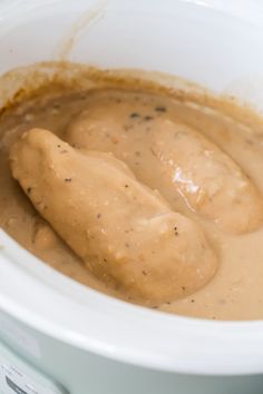 two pieces of meat covered in gravy in a crock pot with sauce