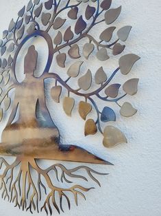 a metal wall sculpture depicting a woman sitting under a tree