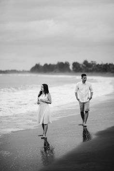 a man and woman are walking along the beach