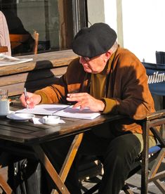 an older man sitting at a table writing