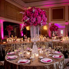 a tall vase filled with pink flowers sitting on top of a table covered in plates