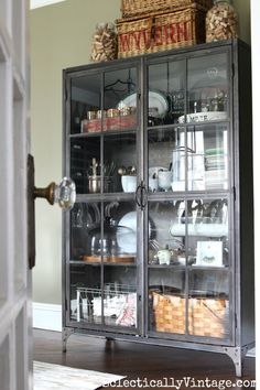 a china cabinet with glass doors and baskets on top