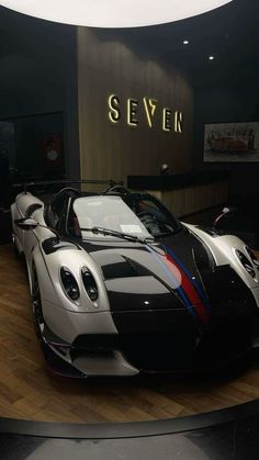 a black and white sports car on display in a museum with the name seven