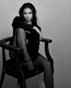 a woman sitting on top of a wooden chair wearing fishnet stockings and high heels