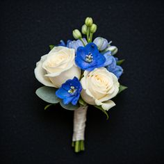 a bridal bouquet with blue and white flowers on a black tableclothed surface