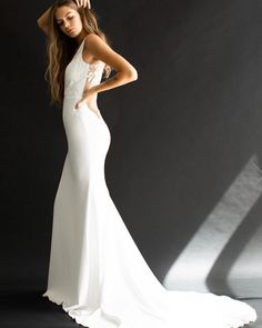 a beautiful woman in a white dress posing for a photo with her hands on her head