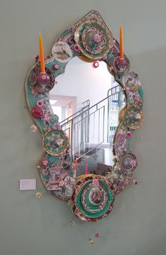 a mirror that is on the wall with candles in front of it and some decorations around it