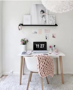 a white desk topped with a laptop computer next to a pink blanket on top of it