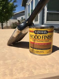 a can of wood finish sitting on top of a table next to a paint brush