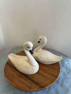 two white swans sitting on top of a wooden table