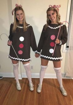 two girls dressed up in costumes standing on a hard wood floor with candy canes