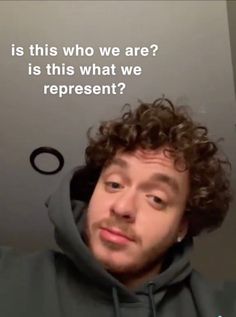 a man with curly hair wearing a grey hoodie