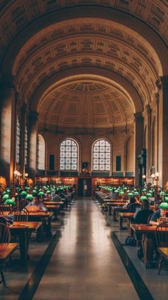 the inside of a library with tables and lamps on either side of the bookshelves