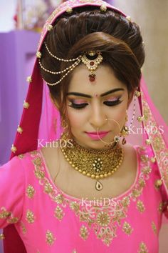 a woman wearing a pink outfit with gold jewelry on her neck and headpieces