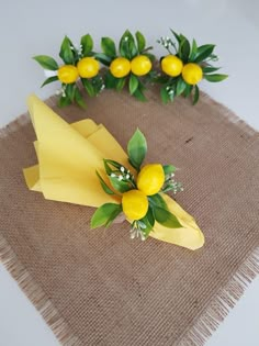 some yellow flowers and green leaves on a burlap table cloth with twine