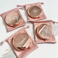 three personalized compact mirrors in pink satin bags on a white table with the name charlotte written on them