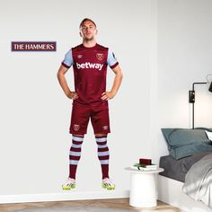 a man standing with his hands on his hips in front of a bedroom wall mural