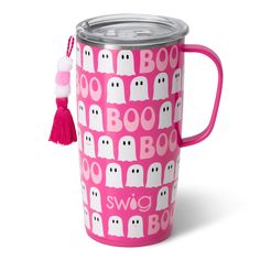 a pink mug with white ghost faces on it and a tassell hanging from the handle