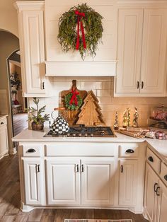 a kitchen decorated for christmas with wreaths on the stove top and other holiday decorations