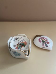 two heart shaped dishes with children's pictures on them, one is white and the other is pink