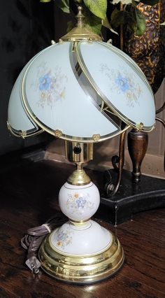 a lamp sitting on top of a wooden table next to a vase filled with flowers