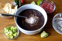 a bowl of black bean soup with tortilla chips and avocado on the side