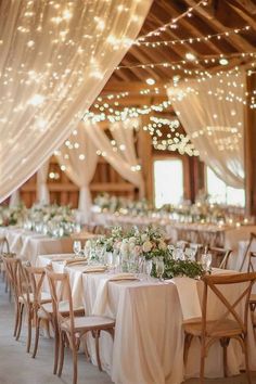 the tables are set with white tablecloths and lights strung from the ceiling above them