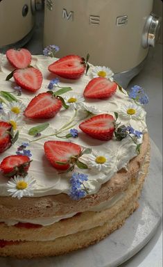 a cake with white frosting and strawberries on top is sitting on a counter