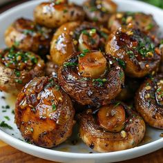 a white plate topped with mushrooms covered in seasoning and garnished on top of a wooden table