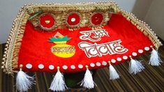 a red and gold purse with tassels on it sitting on a table next to a wall