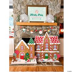 two gingerbread houses are on display in front of a fireplace with a sign above it