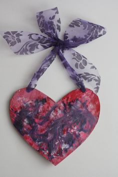 a paper heart hanging from a ribbon on a white background with the words melted crayon art written below it