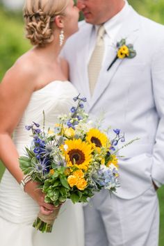 a bride and groom are standing together in front of the grass with sunflowers