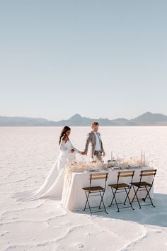 a bride and groom standing at a table in the middle of an empty salt flat