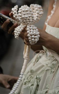 a close up of a woman holding a bouquet of flowers with pearls on it's head