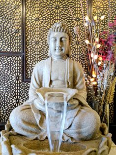 a buddha statue sitting in front of a fountain with water running from it's mouth