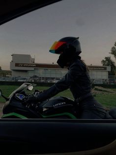 a person riding on the back of a motorcycle in front of a building with a rainbow helmet